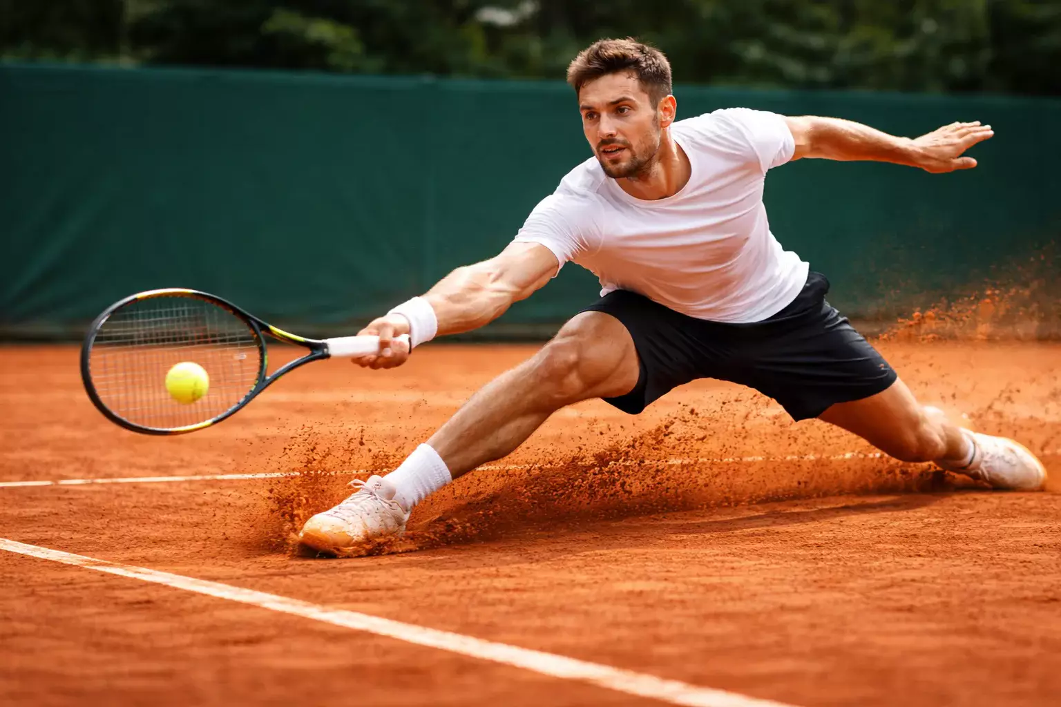 Tenista profesional deslizándose en tierra batida durante un intercambio de fondo